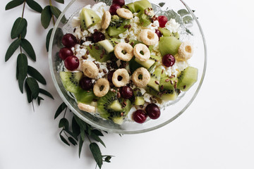 Delicious cottage cheese with kiwi pieces and cranberries in bowl on white background, closeup, healthy breakfas