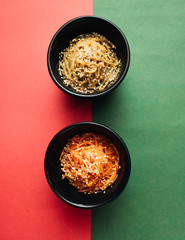 Two bowls with Asian food on red and blue background, top view