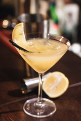 Woman holding delicious cocktail with ice cubes, lemon and straws in bar
