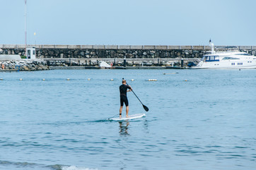 Stand up paddle board man paddleboarding on Peruvian beach standing happy on paddleboard on blue water.