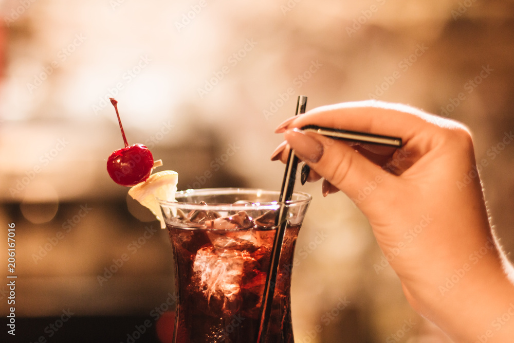 Wall mural delicious cocktail with ice cubes, cherry and straws in bar