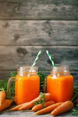 Fresh Carrot and carrot juice on Wooden Table in Garden. Vegetables Vitamins Keratin. Natural Organic Carrot lies on Wooden background.