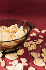 Delicious crispy cornflakes in bowl on red background, healthy breakfast