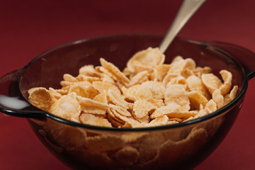 Delicious crispy cornflakes in bowl on red background, healthy breakfast