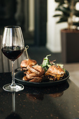 Delicious burgers and wineglass with red wine in cafe