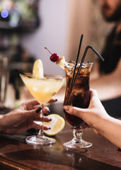 Delicious cocktail with ice cubes, cherry and straws in bar