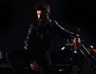 Macho, brutal biker in leather jacket stand near motorcycle at night time. Brutality and masculine...
