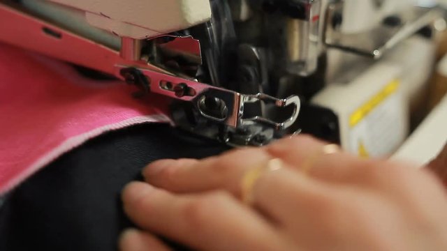 Close-up of woman's hands sewing an overlock at sewing machine.