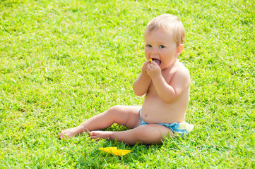 Fun mood. Cute little girl sitting on the grass on a sunny summer day