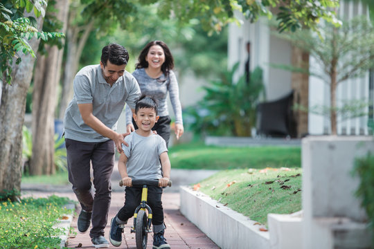 kid with his father learning how to ride a bicycle