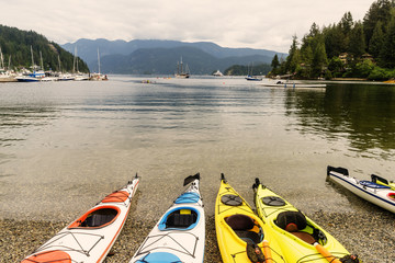 canoes on the pebbles near the clear water, ships and yachts in the background