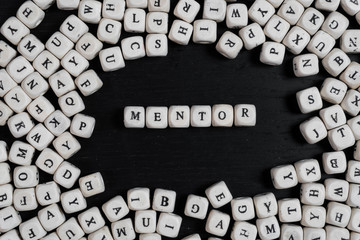Word MENTOR on wooden cubes on a black wooden table