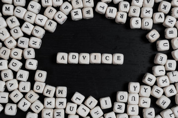 Word ADVICE on wooden cubes on a black wooden table with copy space