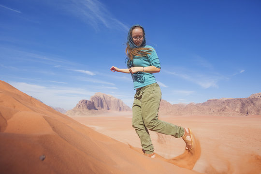young woman with a smile sprinkled sand in the desert