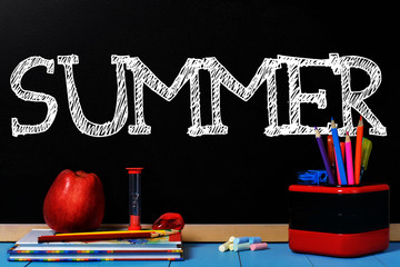 Text Summer on black chalkboard with school accessories