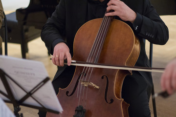 Cello player. Cellist hands playing cello with bow. Violoncello orchestra musical instrument closeup