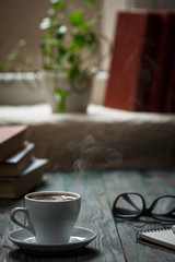 A cup of coffee in the workplace on a wooden table.