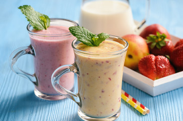 Strawberry and peach milkshakes on blue background.