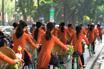 Vietnamese girls wear traditional long dress Ao Dai cycling on Hanoi street