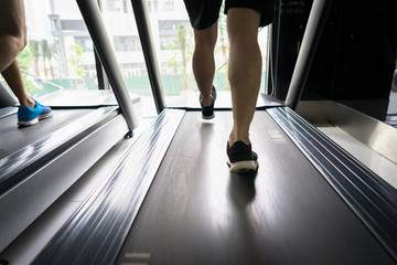 Fototapeta na wymiar Gym treadmill closeup with man legs running. Concept for exercising, fitness and healthy lifestyle
