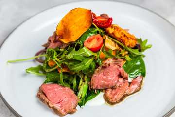 A warm salad with roastbeef, arugula, cherry tomatoes, dried carrot and grilled cheese.
