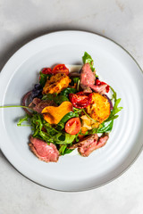 A warm salad with roastbeef, arugula, cherry tomatoes, dried carrot and grilled cheese.
