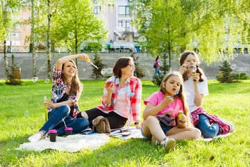 Women with children at sunset resting in the park, picnic, soap bubbles.