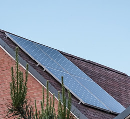 solar panels on the roof of a private house of red brick, roof - brown and lilac bituminous shingles, solar energy, renewable energy, alternative fuel