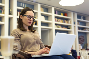 Beautiful brunette woman in glasses working with laptop.