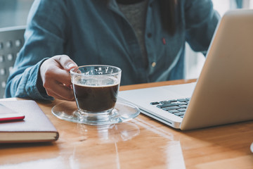 Businesswoman hands holding cups of coffee and using laptop