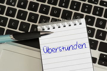 Ein Computer, Stift und Notizblock für Überstunden