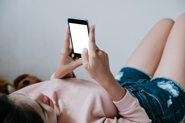 Happy casual beautiful woman relaxing while using smartphone on the bed in the house