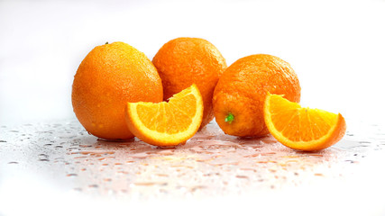 Freshly washed ripe Oranges with cut quarters on a white surface