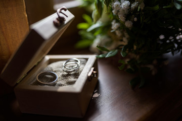 Wedding boutonniere. Gold rings lay in a wooden box.