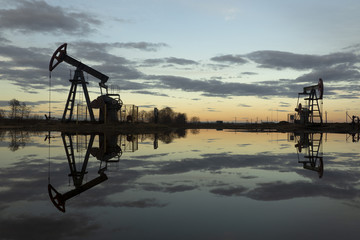 Naklejka premium Industrial pump jack, sunset in oil field