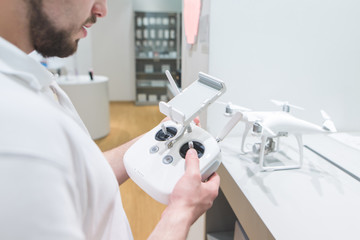 Man with a controller for a drone in his hands at the quadcopter store. Buying a quadcopter in the electronics store.