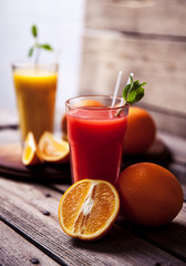 Orange juice in glass with mint, fresh fruits on wooden background a