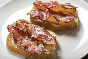 Two slices of fried bread with butter and fried bacon