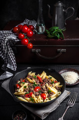 Pasta with tomatoes and meat on  dark rustic background.Selective focus.Vintage style.