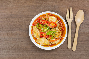 top view of stir fried chicken with roasted chili paste in ceramic dish on wooden table. homemade style hot and spicy food concept.
