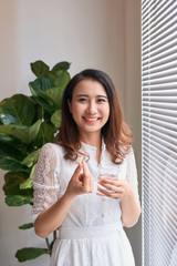 side view of beautiful woman taking vitamin capsule with a glass of water isolated in white