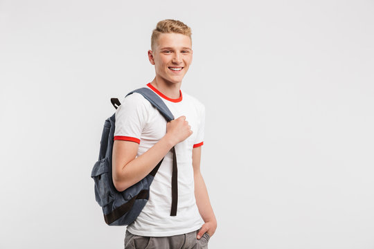 Image of student boy having clean healthy skin wearing casual clothing and backpack smiling at camera, isolated over white background
