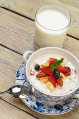Bowl of homemade granola with yogurt and fresh berries on wooden background