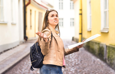 Tourist lost in the city. Confused woman holding map and spreading hands in old town. Disappointed and worried traveler having problem. Frustrated and unhappy during vacation. Wrong way or dead end.