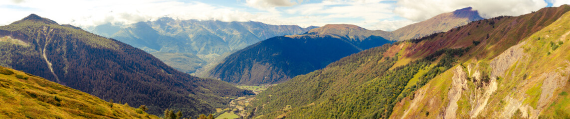 Fototapeta premium Amazing panoramic view to Caucasus Mountains. Densely coniferous forests and high mountain peaks. Sunny day with misty mountains. Svaneti, Geogria.