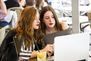 Two young and trendy hipster woman are working in a cafe bar, having an outdoor meeting. Lifestyle conception. 