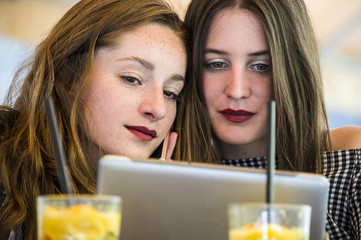 Two young and trendy hipster woman are working in a cafe bar, having an outdoor meeting. Lifestyle conception. 