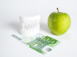 The green apple, the denture and the one hundred euro bill isolated close up