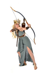 Obraz premium full length portrait of pretty blonde lady wearing fantasy toga gown, and holding a bow and arrow. standing pose on white background.