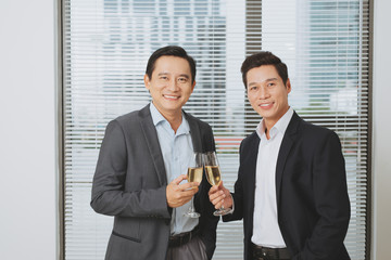 Businesspeople are clanging glasses of champagne or wine